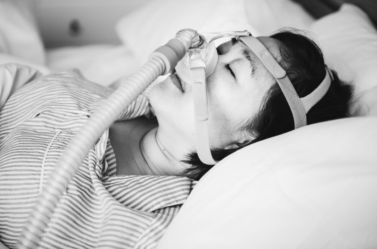resting-peacefully-with-cpap-device-in-hospital-be-2026-03-18-12-08-15-utc - Complete Health Dentistry Patient lying in bed wearing a CPAP breathing mask and head support for treatment.
