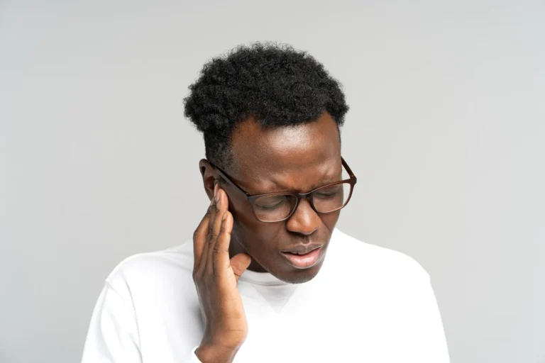 Man touching the side of his head near his ear